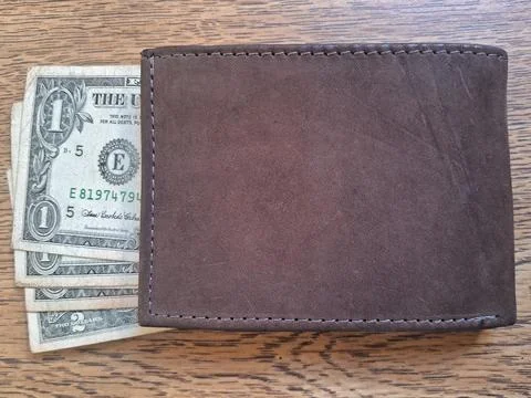 US dollar bills inside a leather wallet on a wooden background. Business Stock Photos