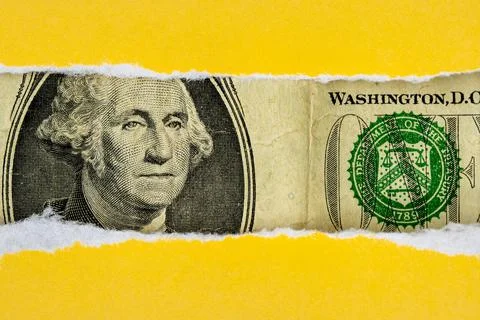 US dollar peeking through torn yellow paper Stock Photos