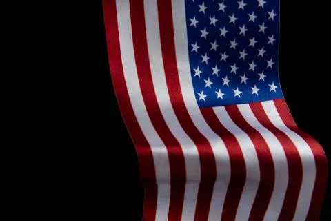 The U.S. flag is developing in the wind against a dark background. Isolate Stock Photos