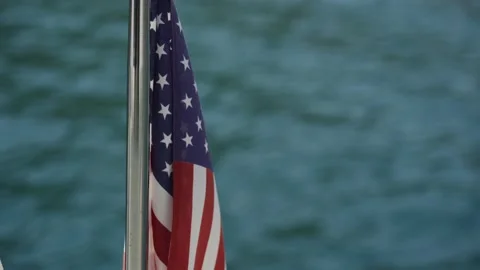 U.S. flag evolves in the wind against water Stock Footage 136965560
