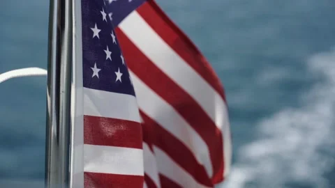U.S. flag evolves in the wind against water in slow motion on the yacht Stock Footage 136965968
