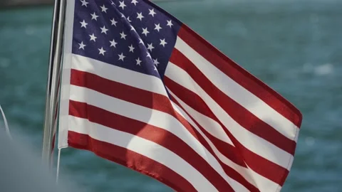U.S. flag evolves in the wind against water in slow motion on the yacht Stock Footage 137115038