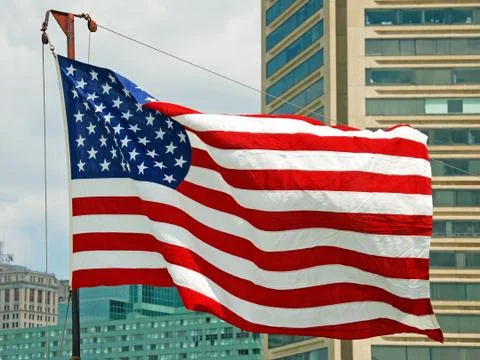 Us flag flapping in wind in baltimore inner harbor in maryland Stock Photos