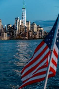 US flag in front of Lower Manhattan skyline at dusk. American flag waving i.. Stock Photos