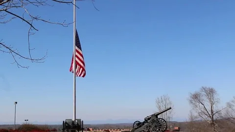 US Flag at Half Mast over Artillery Canon and Blue Skies Stock Footage 69232134