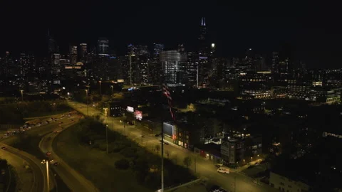 US Flag with the night lit Chicago skyline in the background - circling, Stock Footage 240842729