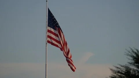 US flag waving from a pole at dusk, with birds flying by Stock Footage 90232557