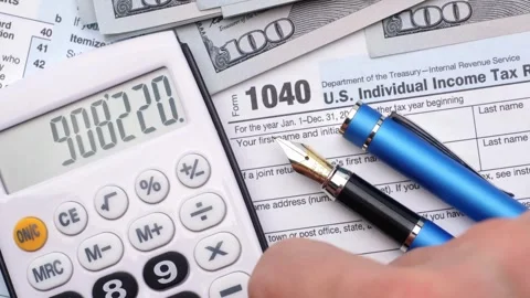 US Income Tax Return forms 1040 paper with calculator. person filling Taxat.. Stock Footage 272783990