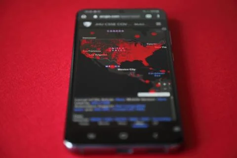 US map of coronavirus confirmed cases on the smartphone screen, red background Stock Photos