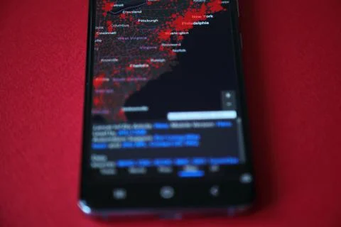 US map of coronavirus confirmed cases on the smartphone screen, red background Stock Photos