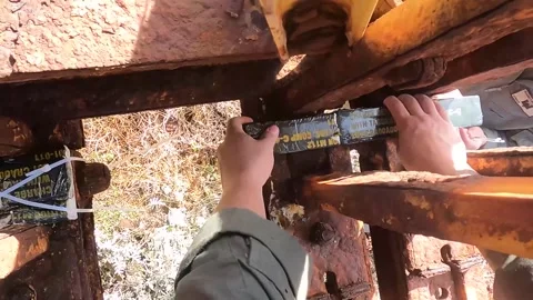 U.S Marine laying M112 explosive on rusted beam of Bailey Bridge for demolition Stock Footage 261512650