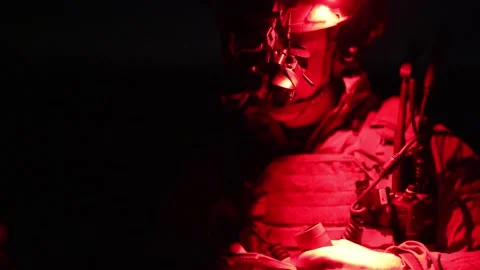 U.S. Marine referencing a notepad while wearing infrared night vision goggles Stock Footage 295620497