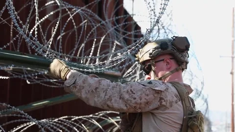 U.S. Marine securing coils of razor wire to southern border wall Stock Footage 301195134