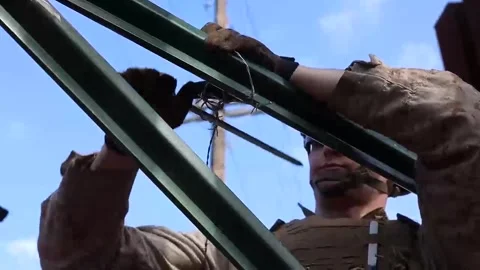 U.S. Marine securing razor wire to Mexican border wall for enhanced security Stock Footage 300966145