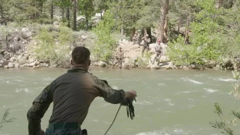 U.S. Marine throwing rope across river to conduct river crossing Stock Footage 277686471