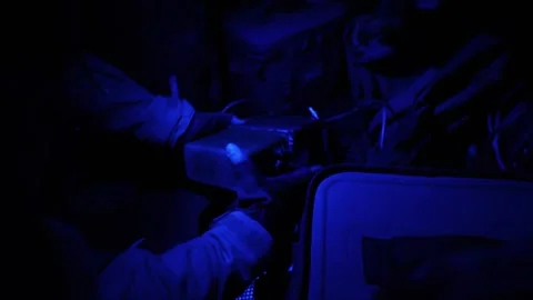U.S. Marine using blue night vision light to assemble radio transmitter Stock Footage 254557594