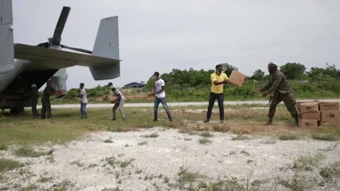 U.S. Marines and Haitians offloading boxes of food from MV-22 Osprey Stock Footage 161794615