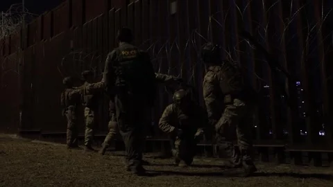 U.S. Marines attaching razor wire to the Mexican border fence during the night Stock Footage 300260978