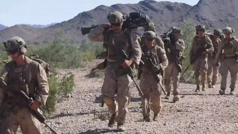 U.S. Marines carrying weaponry through desert during assault raid exercise Stock Footage 254065997