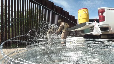 U.S. Marines prepare coils of razor wire during barrier reinforcement operations Stock Footage 334839014