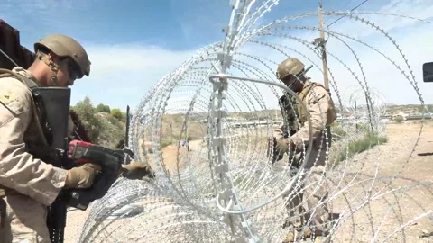U.S. Marines prepare coils of razor wire during barrier reinforcement operations Stock Footage 334839026