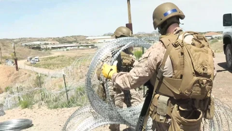 U.S. Marines prepare coils of razor wire during barrier reinforcement operations Stock Footage 334841725