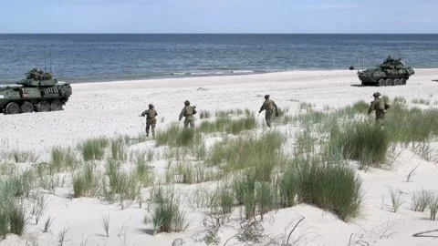 U.S. Marines running down beach towards armored vehicles Stock Footage 278147936