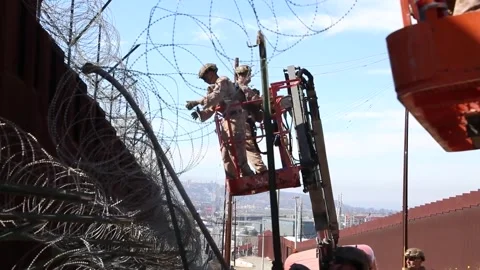 U.S. Marines securing razor wire to border wall from mobile elevated platform Video stock 301195210