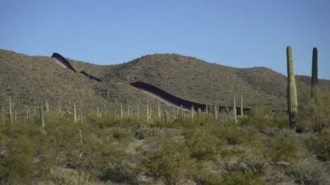 The US Mexico border wall rising over hilly terrain in Arizona Stock Footage 237000109