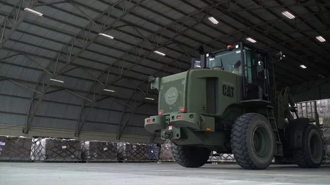 US military cargo loader moving supplies inside warehouse Stock Footage 83271546