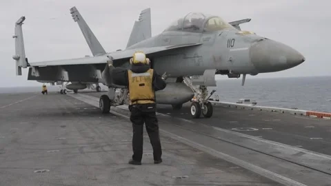 U.S. Navy aircraft handler directing F/A-18 Hornet aboard USS Nimitz Stock Footage 292634774