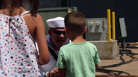 U.S. Navy sailor kneeling down speaking to son on return home from deployment Stock Footage 279727908
