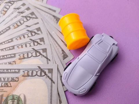 US one-hundred-dollar bills fanned out next to a white toy car and a yellow.. 스톡 사진