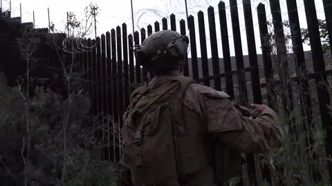 U.S. service member inspects the border wall for signs of breaches during patrol Stock Footage 334376997