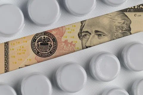 US ten dollar banknote visible between white medicine blister packs represe.. Stock Photos