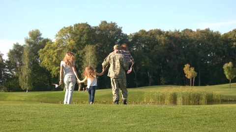 US veteran in camoubackgrounde with family walking away. Stock Footage