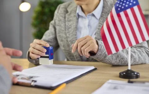 US visa documents approval by consulate officer at desk with United States flag 스톡 사진