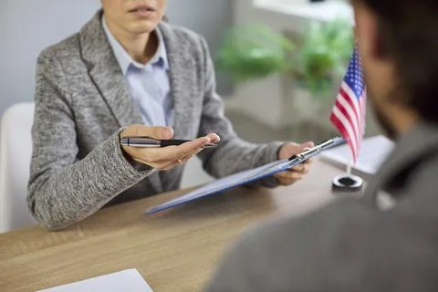 US visa interview at consulate, officer reviewing documents at desk with USA 스톡 사진