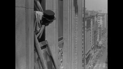 USA - 1930 - In this comedy, a man (Harold Lloyd) hanging from an active fire Stock Footage 341338346