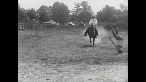 USA - 1930 - A man does a handstand as a horse rider rides by. He lassos the Stock Footage 327739405