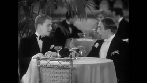 USA - 1930 - In this musical comedy, two men sit at a fancy restaurant and talk Stockbeeldmateriaal 325206352
