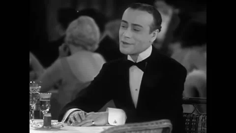 USA - 1930 - In this musical comedy, two women sit with a man at a fancy Stock Footage 325209300