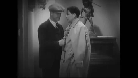 USA - 1932 - In this pre-code drama, a man puts a trench coat over a tied up man Stock Footage 327740473