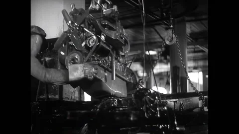 USA - 1936 - An engine is lowered into a car frame. Large sheet metal is pressed Stock Footage 327741420