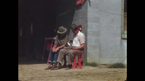 USA - 1950s - Two men read a pamphlet about horse racing. A jockey preps a 库存影片 327752105