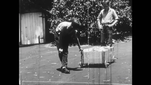 USA - 1958 - Two boys roll a crate of comics on wooden wheels. A wagon wheel is Stock Footage 327754819