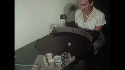 USA - 1972 - A machine spins a silver dollar in front of a woman and they try Stock Footage 327735481