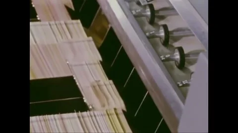 USA - 1972 - Machines stack paper at a data processing center and a woman files Stock Footage 259378445