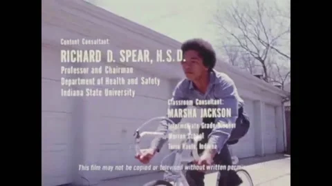 USA - 1976 - A cop pulls over a young African-American cyclist for running a Stock Footage 261569112
