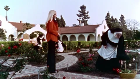 USA - 1977 - In this sci-fi horror, a nun offers a rose to a woman in a garden. 스톡 동영상 327748025